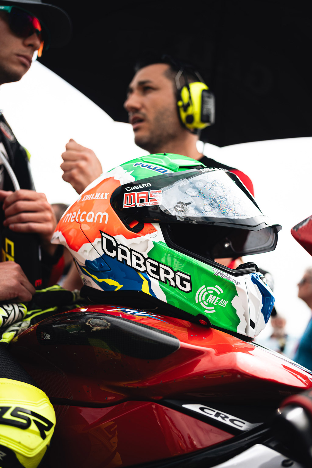 casco caberg Gp01 con grafica tricolore appoggiato sul serbotaoio di una moto da corsa
