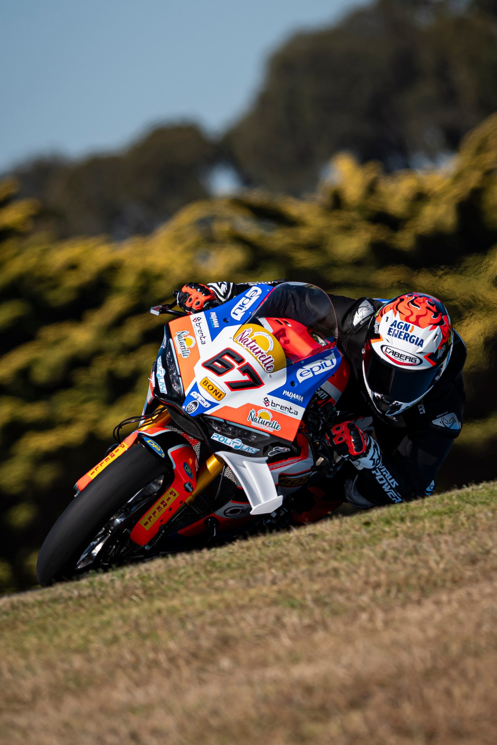 Pilota in curva in pista con casco Caberg GP01 Carbon omologato FIM Level 2 durante gara racing