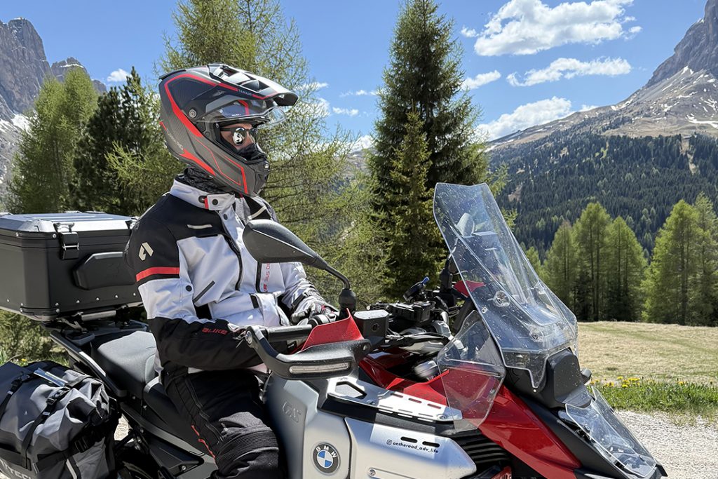 A man on a motorcycle wearing the Caberg TANAMI Carbon helmet and sunglasses