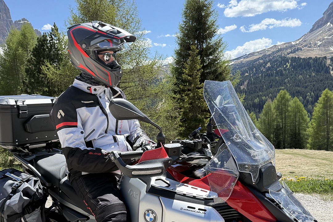 A man on a motorcycle wearing the Caberg TANAMI Carbon helmet and sunglasses